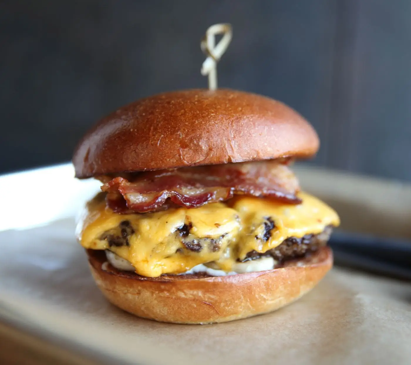Bacon cheeseburger with melted cheddar on a toasted brioche bun