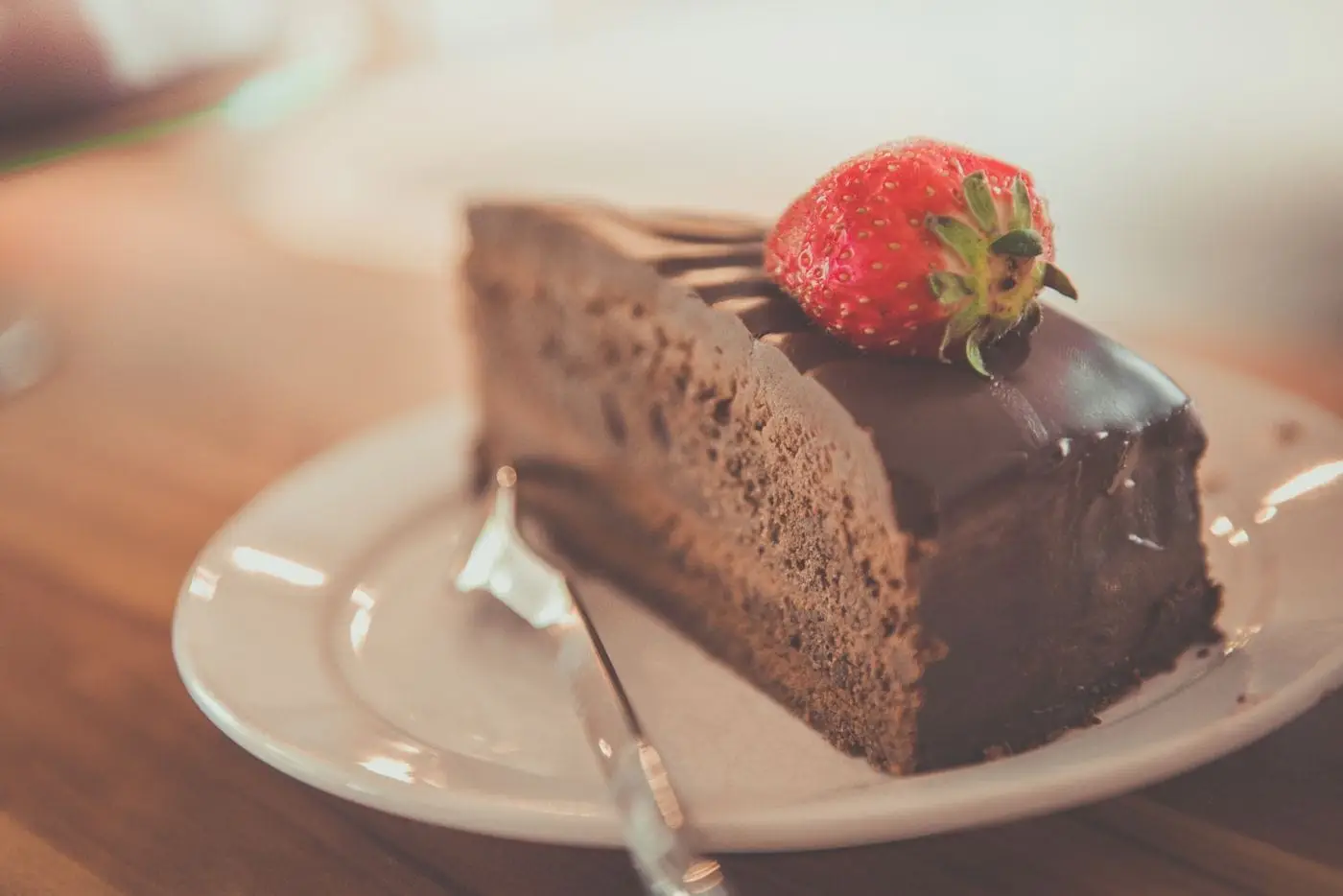 Slice of chocolate layer cake topped with a fresh strawberry