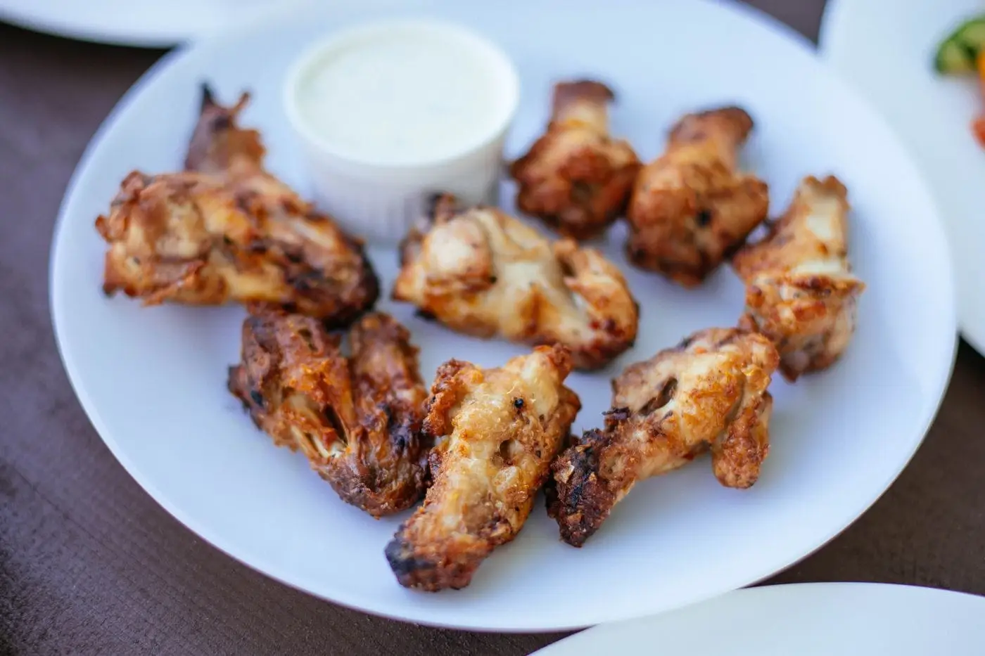 Plate of crispy bone-in chicken wings with a ranch dipping sauce