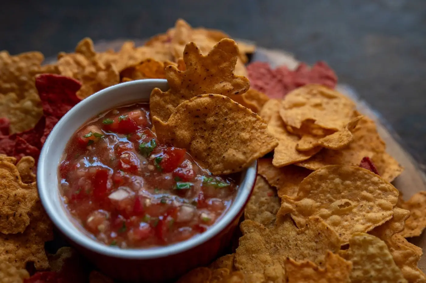 Tortilla chips surrounding a bowl of fresh tomato salsa
