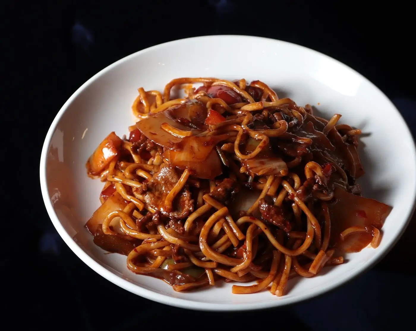 Stir-fried noodles with beef and vegetables in a white bowl