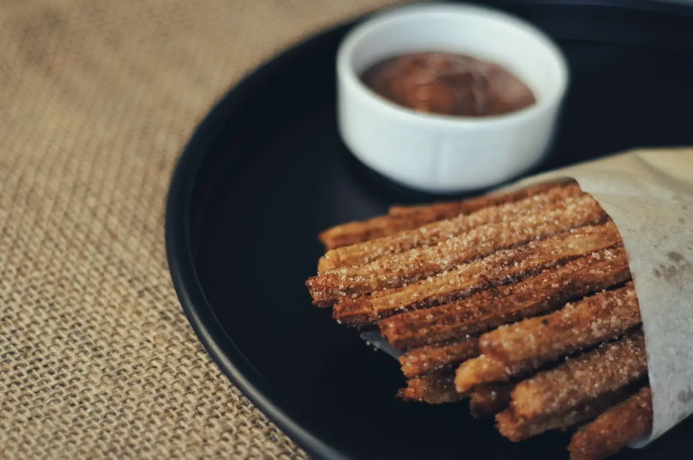 Cinnamon sugar churros in paper with a chocolate dipping sauce