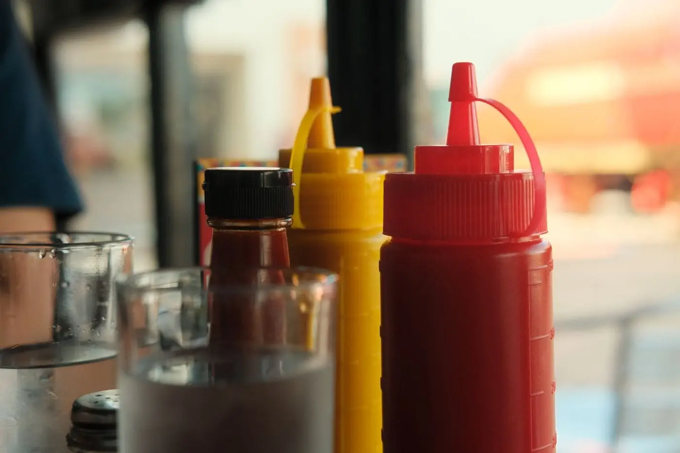 Red ketchup and yellow mustard squeeze bottles on a diner table