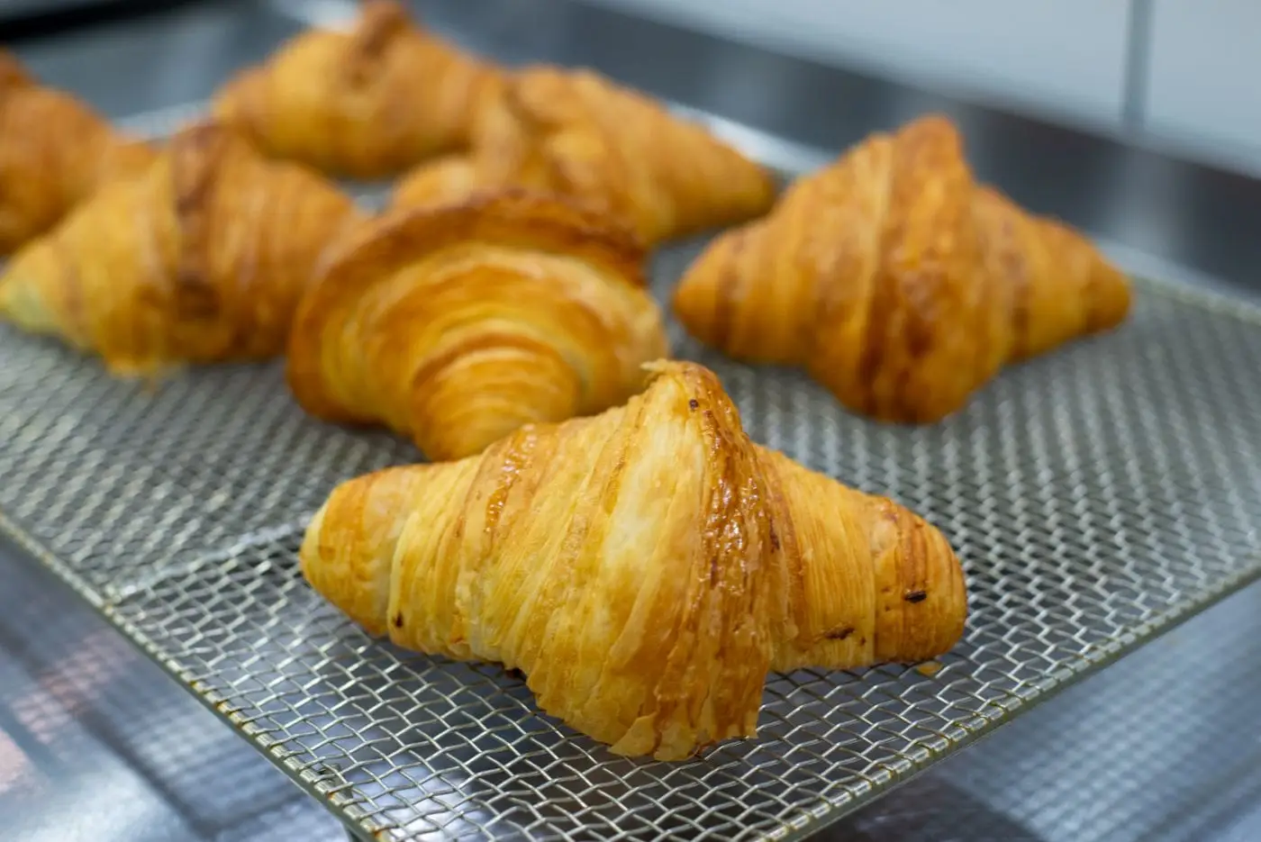Golden flaky croissants cooling on a wire rack
