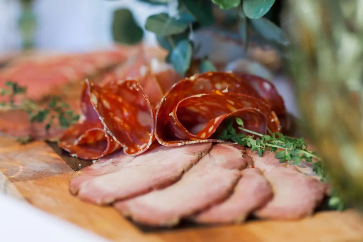 Thin slices of salami and smoked ham on a wooden board