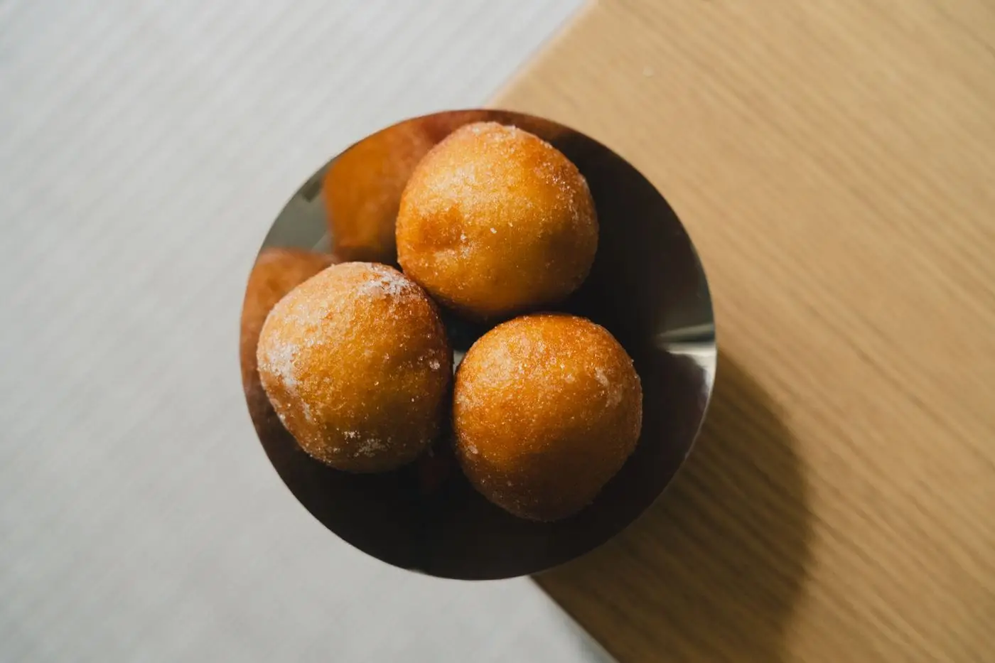 Sugar-coated fried dough balls in a bowl, seen from above