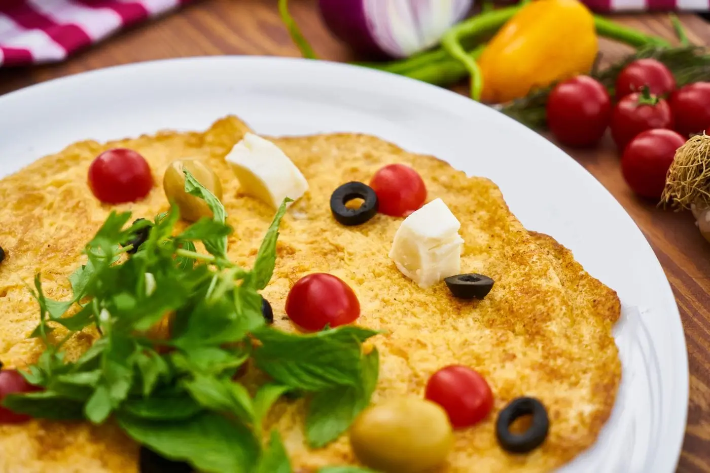 Omelette topped with cherry tomatoes, olives, feta cheese and fresh herbs