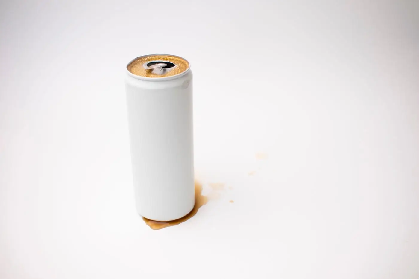Plain unbranded white drink can, opened, with a small spill on white