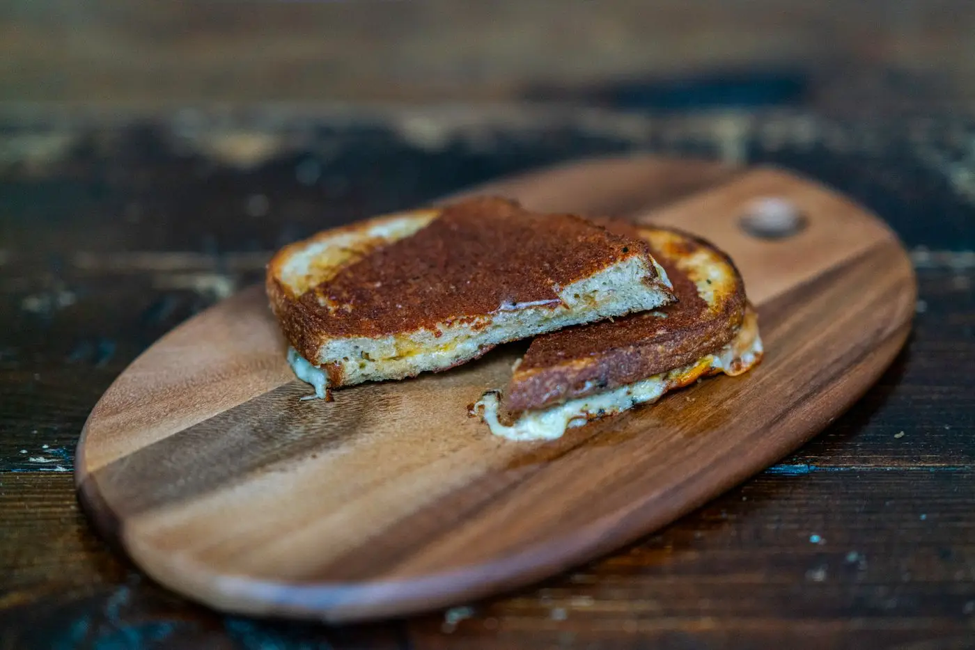 Grilled cheese sandwich cut in half on a wooden serving board