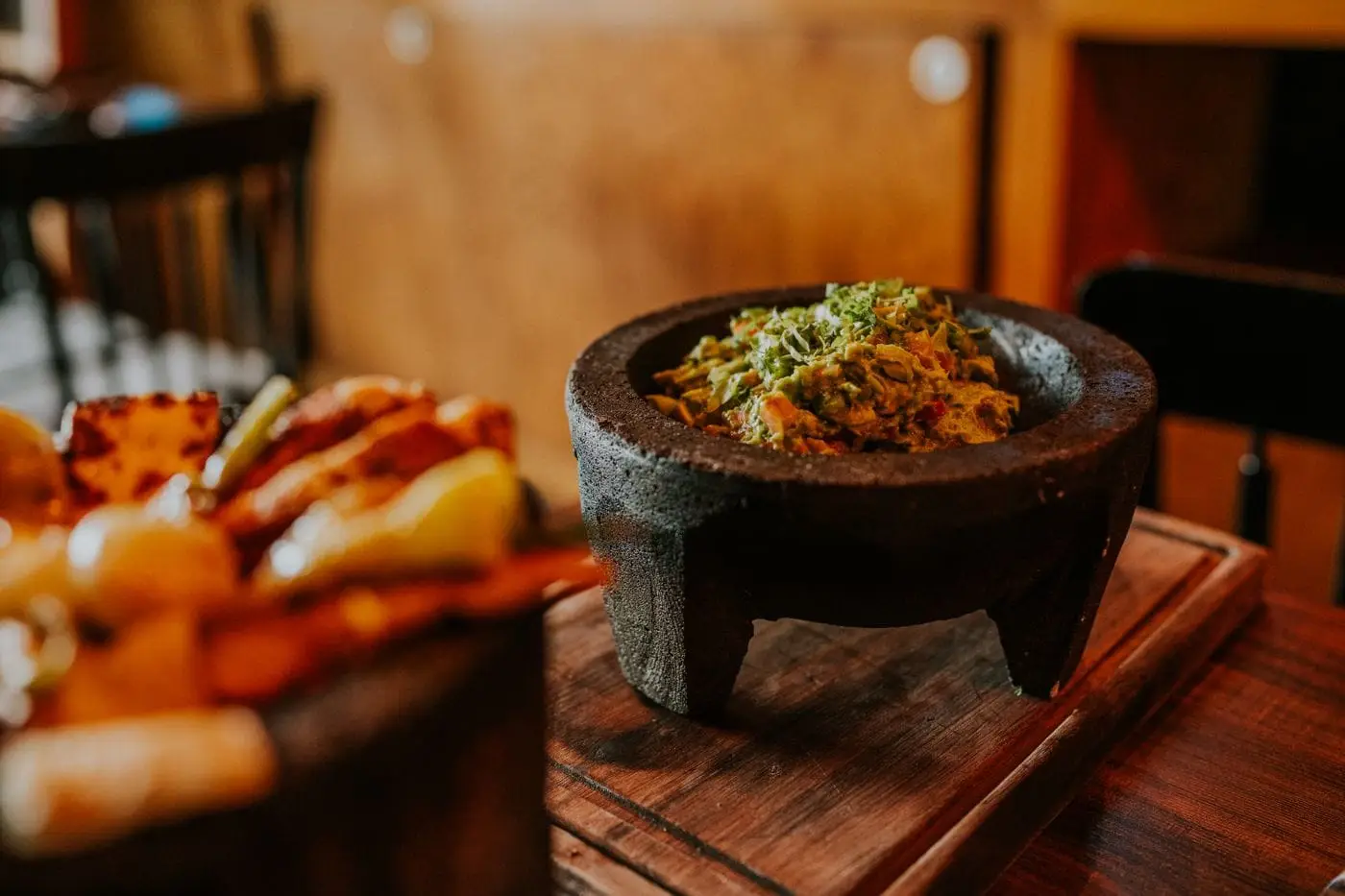 Guacamole in a rustic stone molcajete on a wooden table