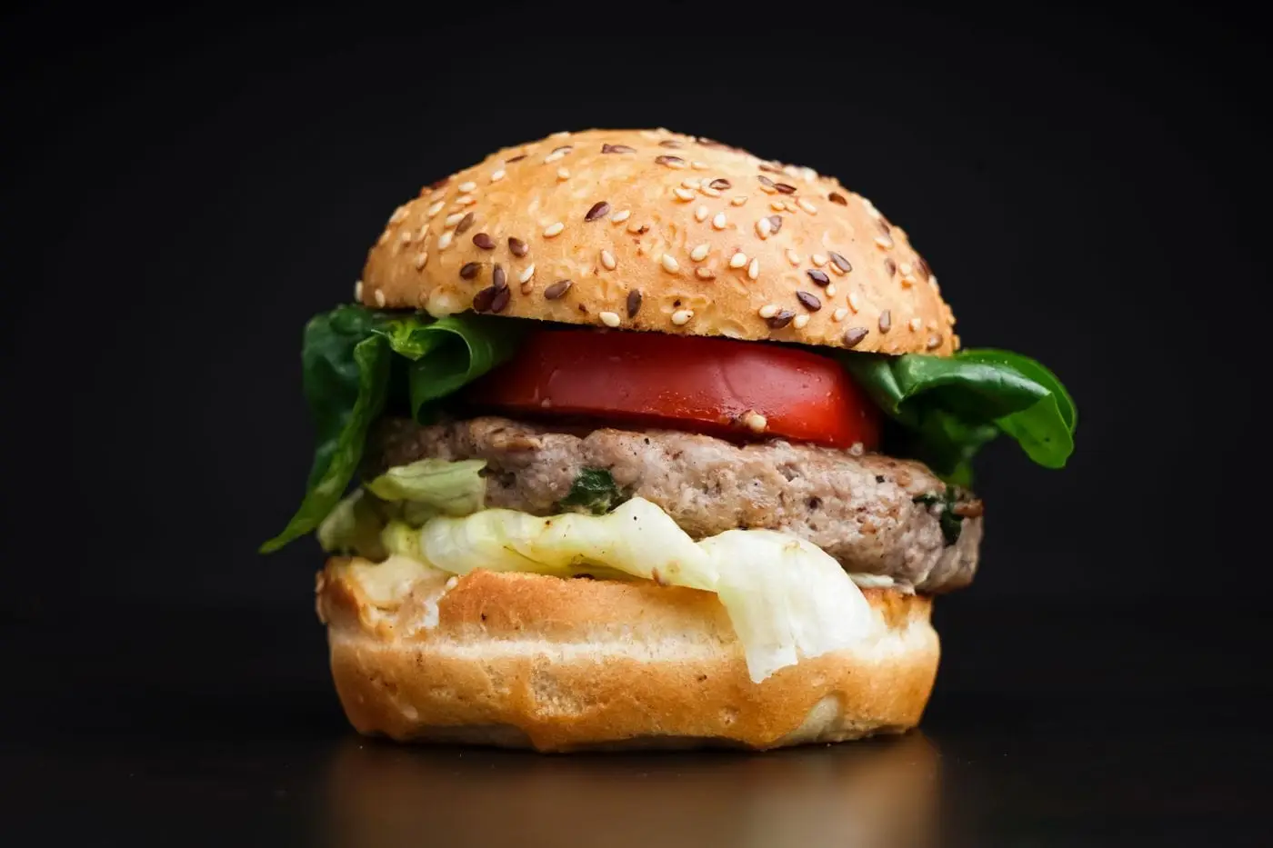 Hamburger with tomato, lettuce and spinach on a sesame seed bun