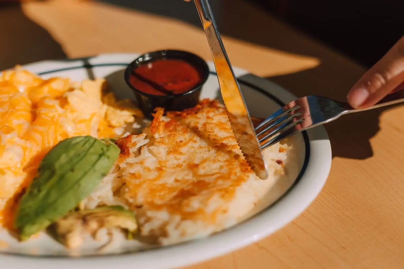 Crispy shredded hash browns with scrambled eggs and avocado on a plate
