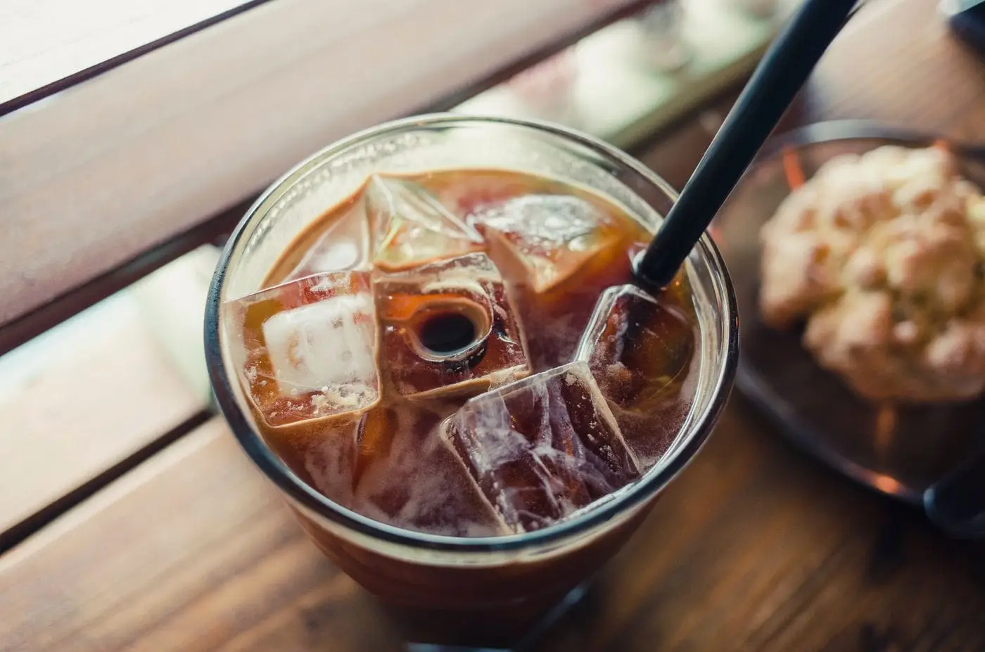 Iced black coffee with ice cubes and a black straw in a glass