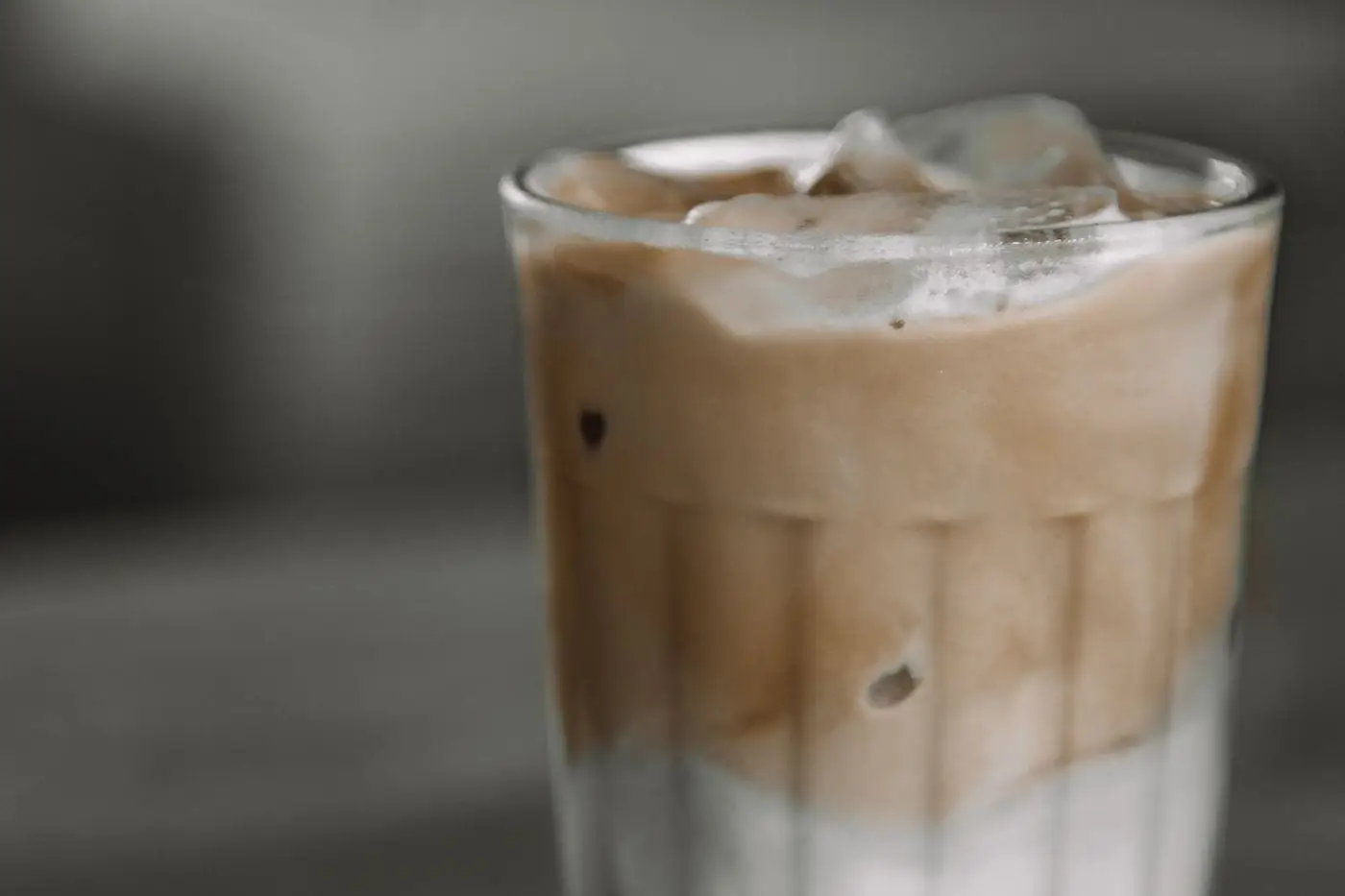 Iced latte with coffee and milk layers over ice in a clear glass