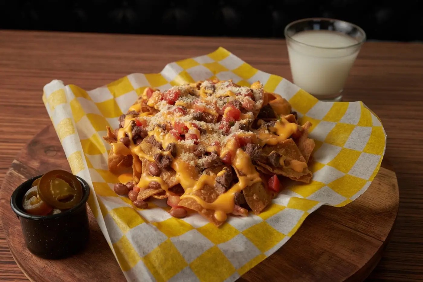 Nachos topped with melted cheese, beans and beef on checkered paper