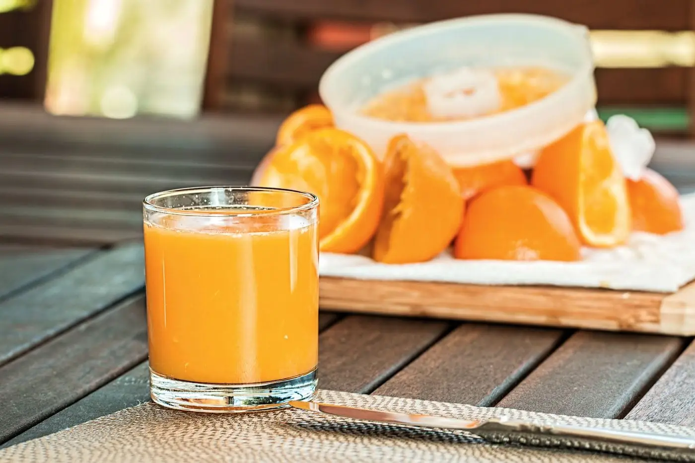 Glass of fresh orange juice in front of squeezed orange halves