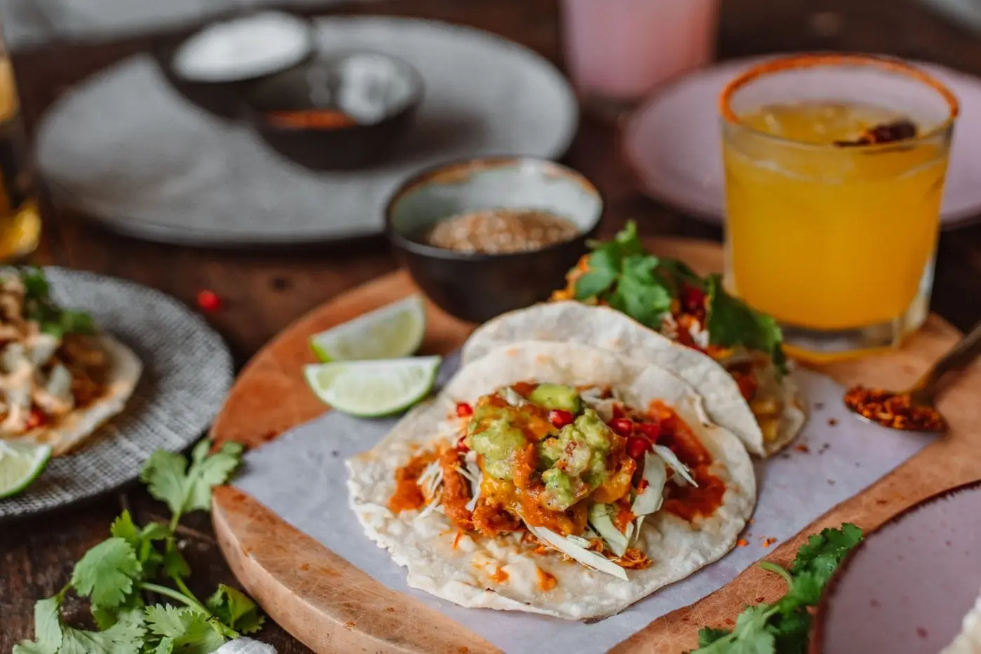Soft tacos with guacamole and salsa on a wooden board with lime