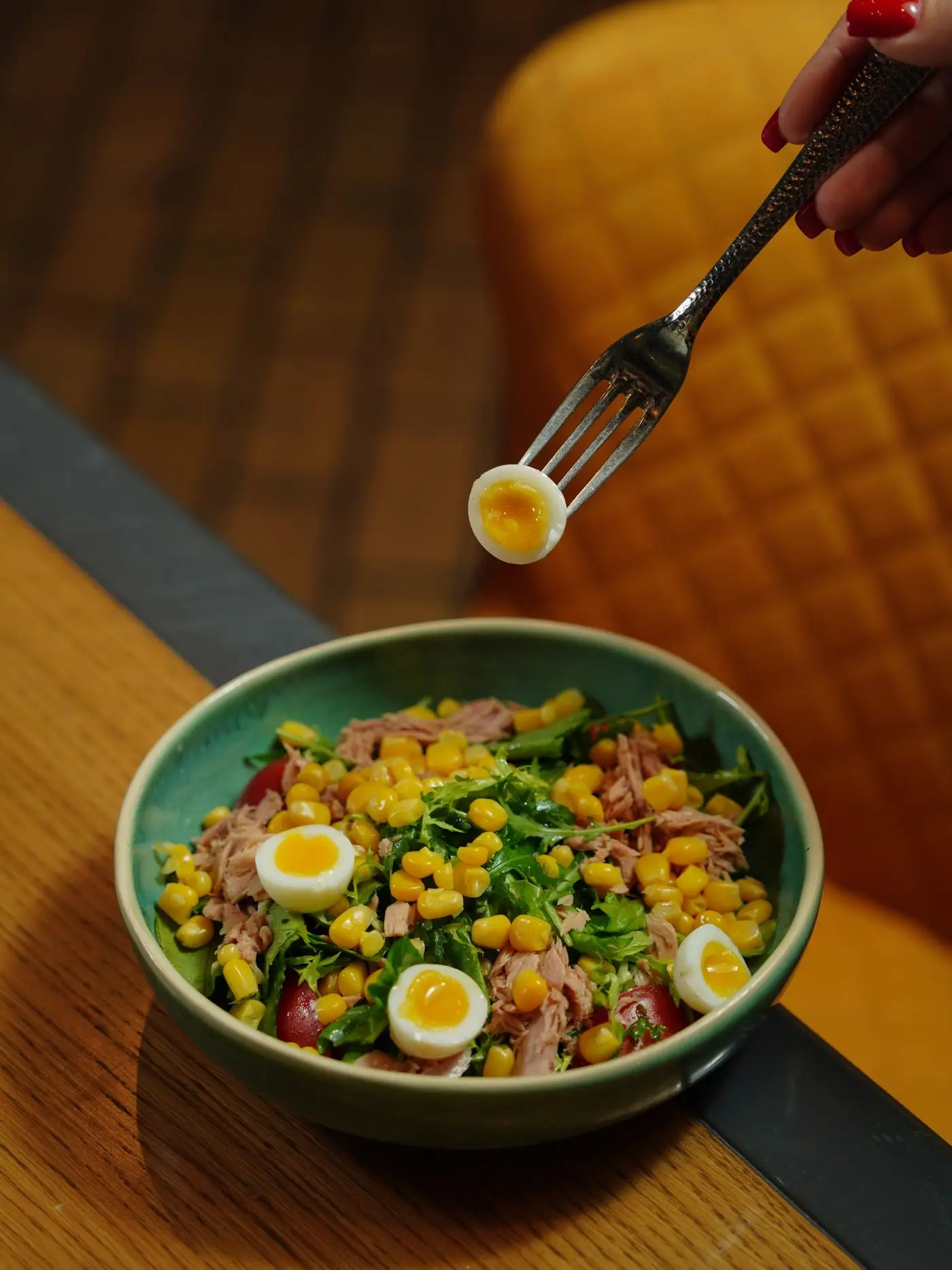 Bowl of tuna salad with corn, greens and halved quail eggs